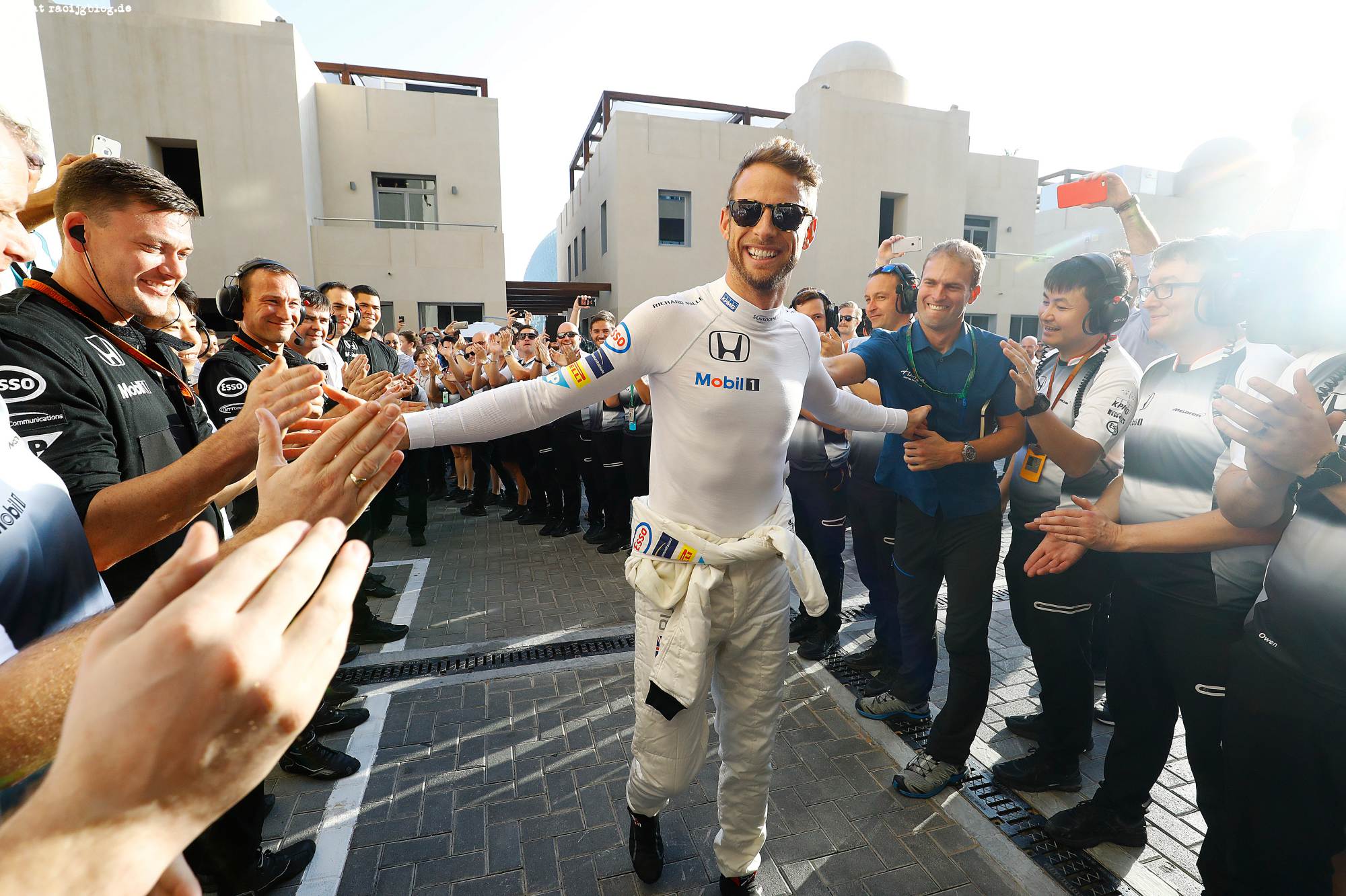 Jenson Button walks to the garage to the cheers of his team.